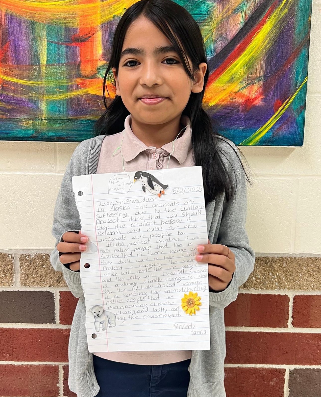 A student proudly holding up her finished writing