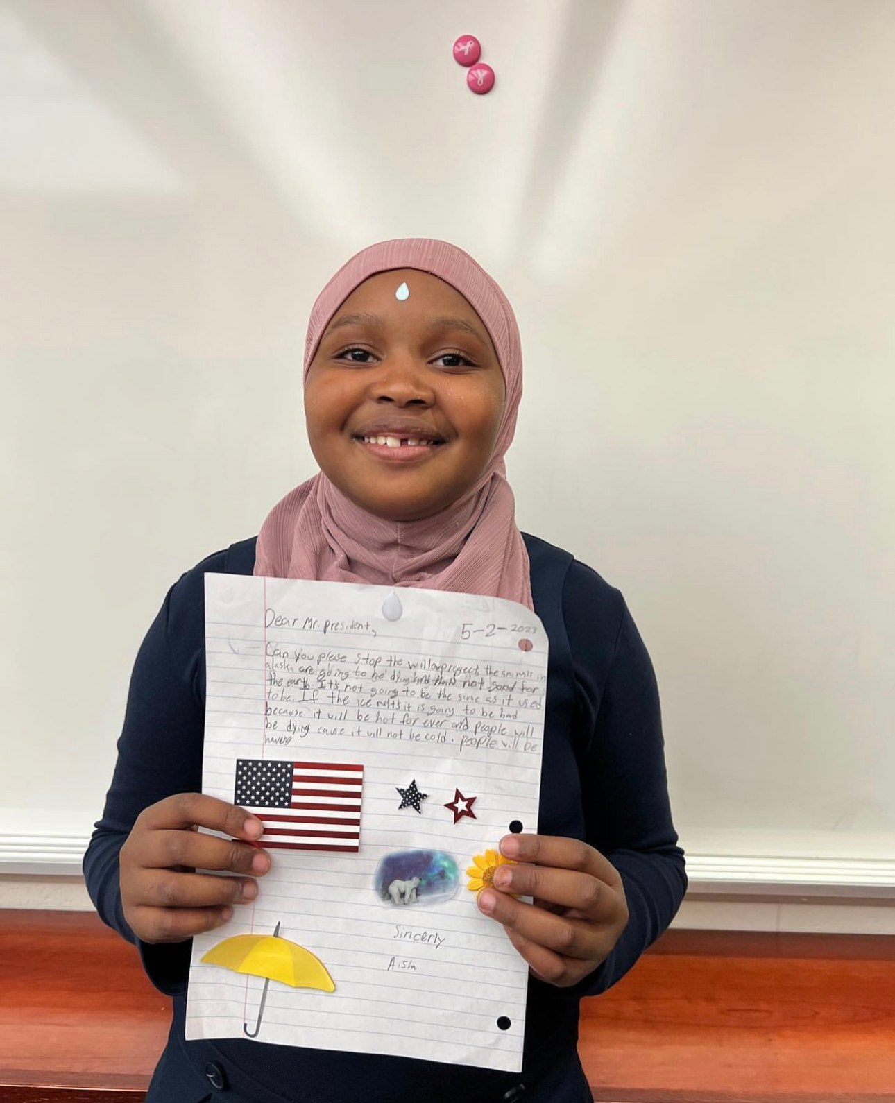 A student smiling and holding up his work