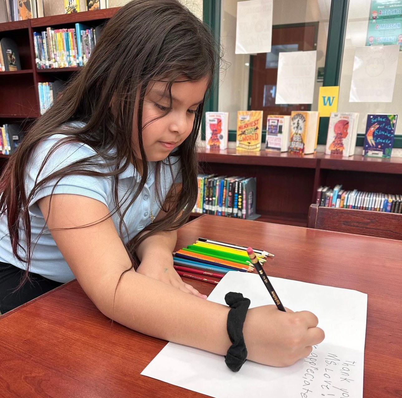 A student writing with colored pencils nearby