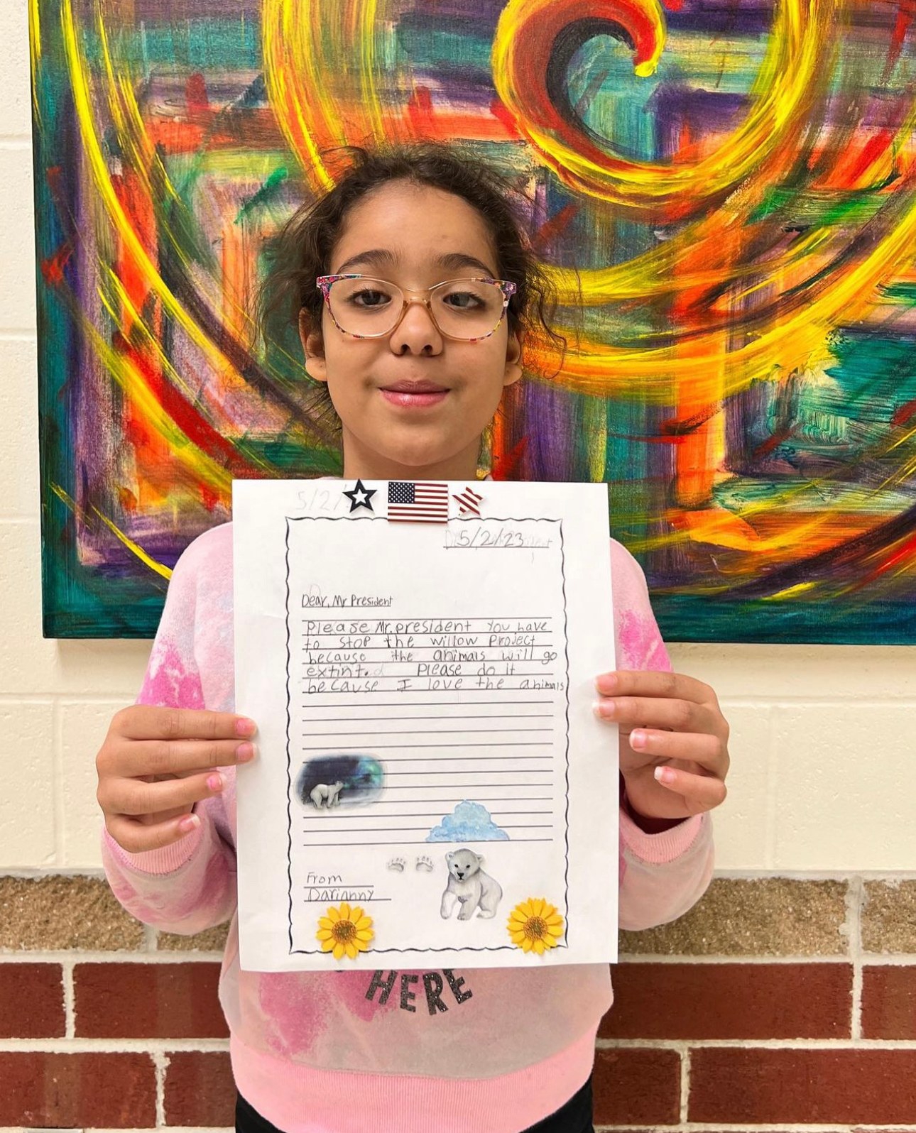A student holding up her illustrated page