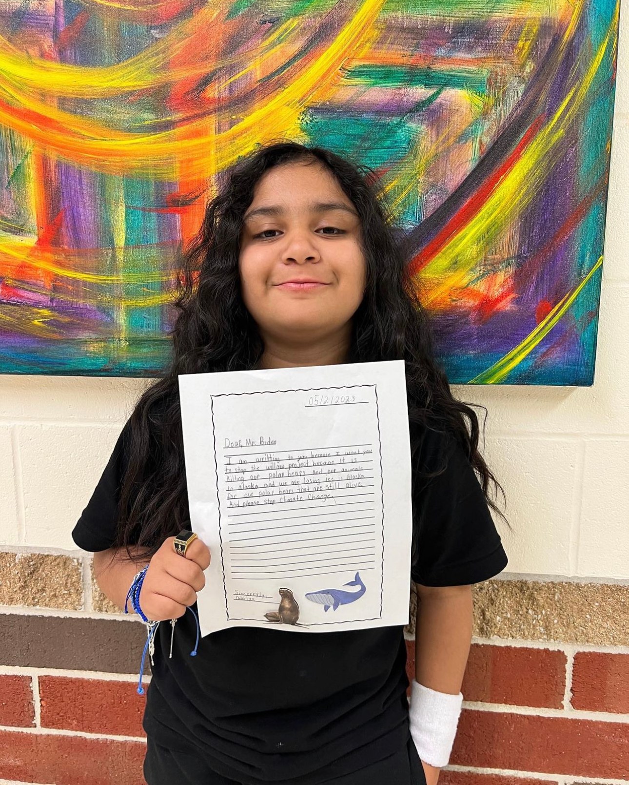 A student holding up her essay in front of a mural